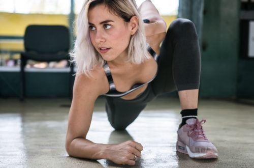 Focused woman with blond hair stretching indoors, showcasing determination and fitness.